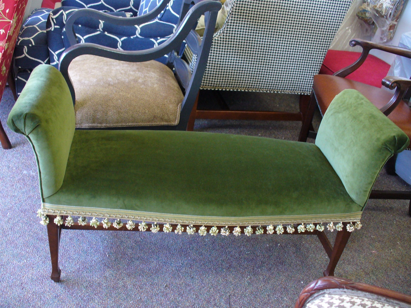 Green upholstered bench with decorative fringe